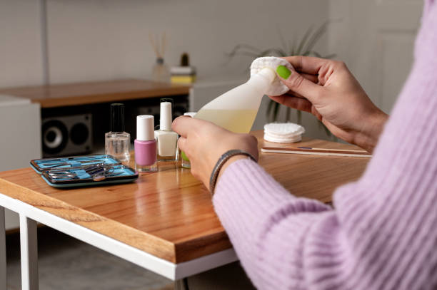 Woman using nail polish remover while doing manicure at home stock photo