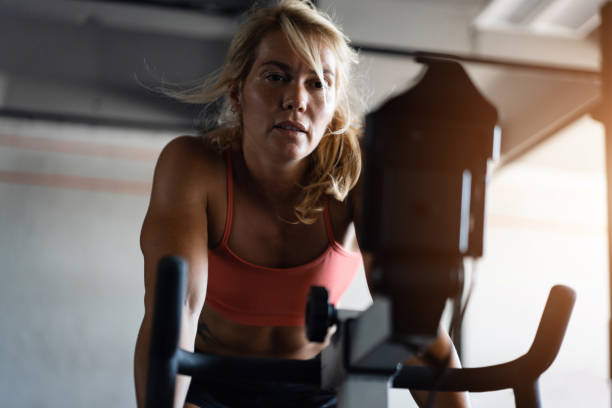 istock Active sportswoman, exercising on the stationary cycling machine 1414247672