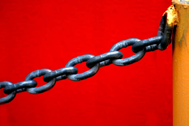 istock Chain Hanging from Yellow Pole with Red Wall Background 1414248055