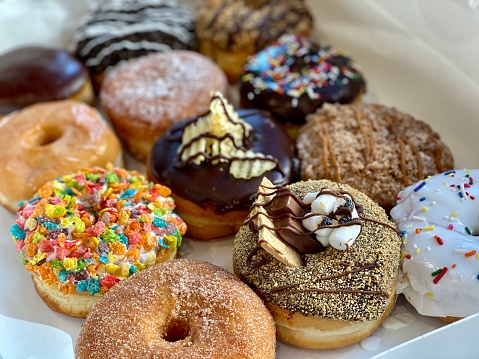 Delicious donuts (pictured in selective focus) topped with a variety of sweet and colorful toppings.