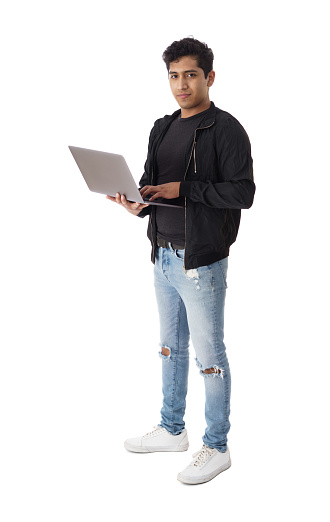 Full shot of male student holding and using a laptop computer with a smile.