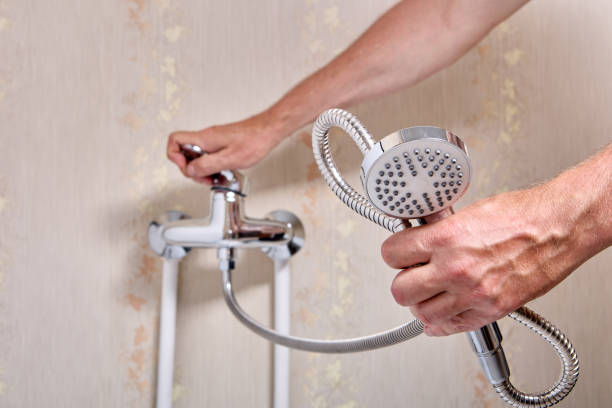 Plumber fixing leaky single handle shower faucet in bathroom.