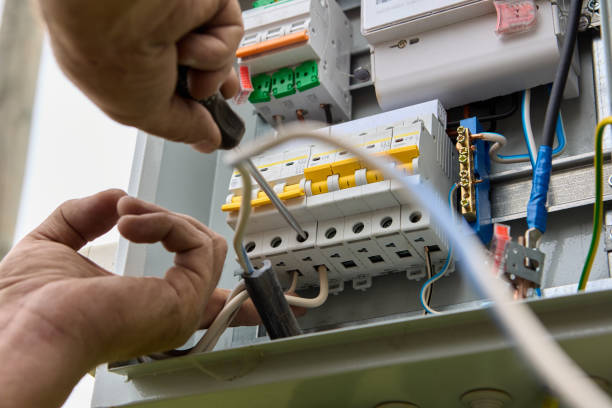 istock Fastening circuit breakers to DIN rail of consumer unit of electrical panel. Mounting fuse box for distribution board. 1414250853