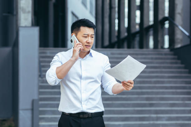 istock Frustrated insurance agent with documents talking on the phone outside the office 1414253633