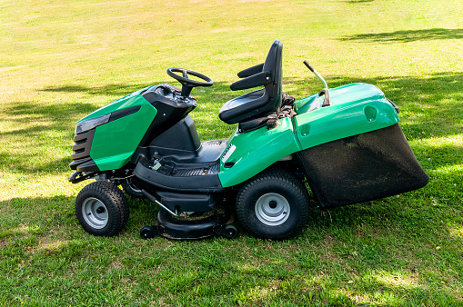 Red lawn mower in lush green grass mowing lawn cutting