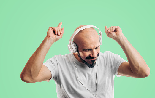 Studio portrait of a handsome young man using headphones against a white background