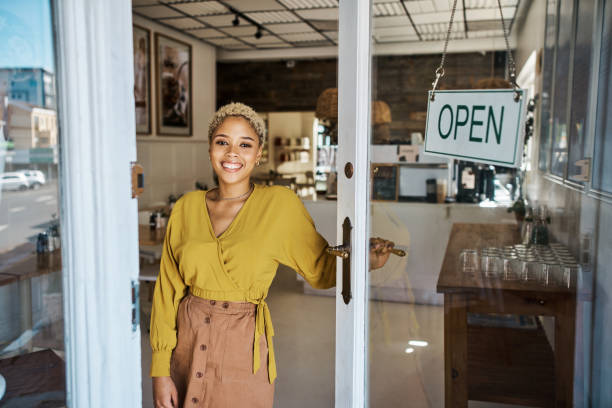 istock Cafe owner, open for business and customer server. Successful, professional and small store owner or manager standing at the door of the coffee shop. Young and female entrepreneur enjoys working. 1414263260