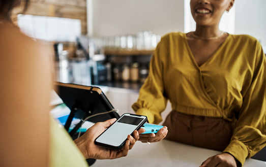 Payment, customer and contactless technology while tapping phone to pay her bill in a coffee shop. Hands of woman using secure banking app to pay for service in a local cafe for smart spending
