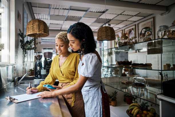 Startup entrepreneurs planning menu and preparing a budget for coffee shop, making notes on clipboard in cafe kitchen. Small business and restaurant owners doing an audit, checking product inventory. stock photo
