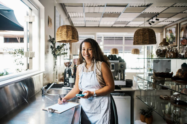 unternehmer oder kleinunternehmer, der im startup-café oder -geschäft inventarisierung, gewinnanalyse oder angebotsmanagement durchführt. erfolgreiches gesichtsporträt von einzelhandelsmitarbeitern, die an der lagerbestellung in der e-commerce-app arbe - looks back stock-fotos und bilder