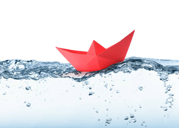 istock Handmade red paper boat floating on clear water against white background 1414263419