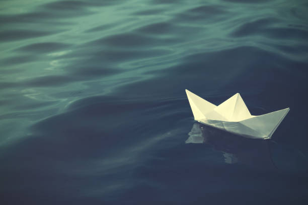 istock White paper boat floating on river. Retro photo effect 1414263606