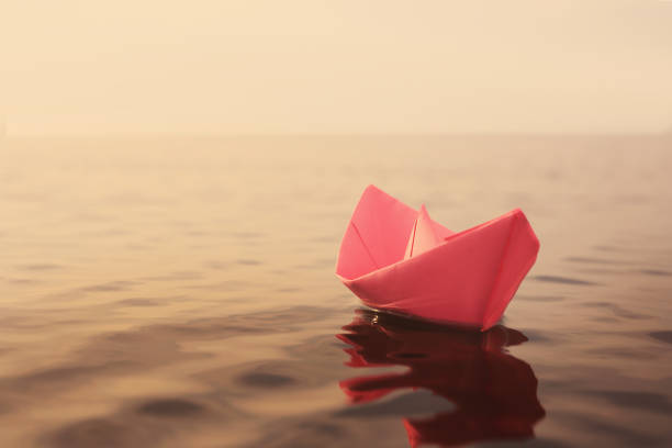 istock Pink paper boat floating on river. Retro photo effect 1414263626