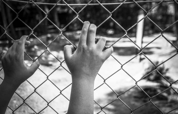 Refugee child's hand on the wire at the border
