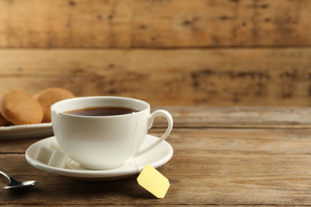 istock Tea bag in ceramic cup of hot water on wooden table. Space for text 1414265455