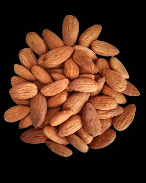 Image of Sweet Almond Badam, an edible and widely cultivated nut of  Prunus dulcis tree, in heap in black background