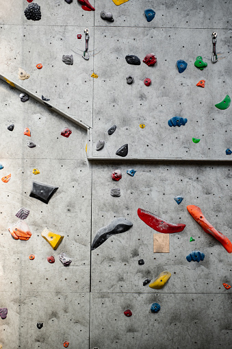 Close up photo of a rock climbing wall with climbing holds in gym.