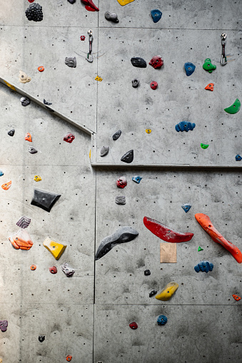 Caucasian men and women in teens and 20s working together in practice sessions moving up vertical walls in sport climbing gym.