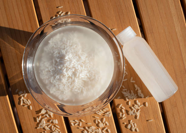 Bowl with rice and bottle of homemade rice water on wooden table. DIY skincare product. Bowl with rice and bottle of homemade rice water on wooden table. DIY skincare product. Top view. drenched stock pictures, royalty-free photos & images