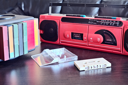 Close up view of an old cassette player and radio with audio compact cassette in front of it.