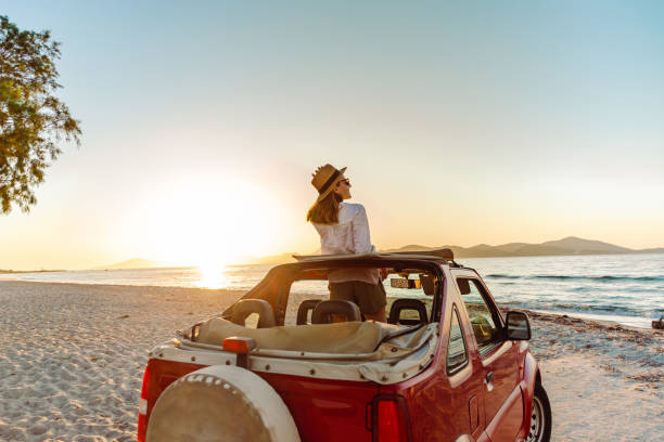 mujer joven disfrutando del viaje por carretera junto al mar - alquiler de coche fotografías e imágenes de stock