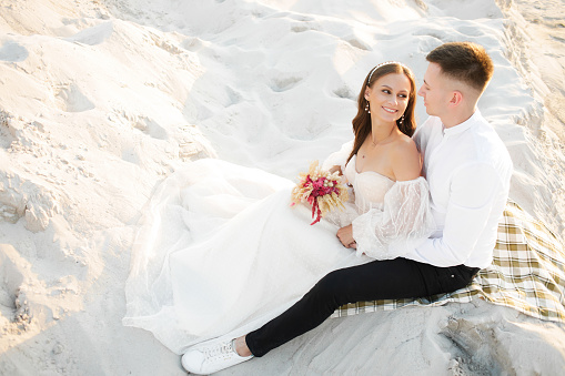 Love Story of a beautiful couple in a wedding luxury dress with a bouquet in the  desert, sand, dunes