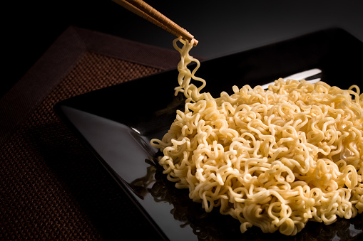 Sophisticated Japanese Ramen or Chinese Nodles (without vegetables) on a black plate, on a dark table.