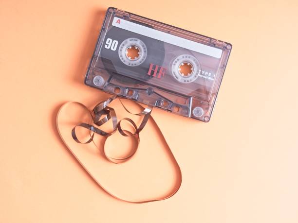 istock Fouled audio cassette tape with magnetic media spooled on orange background 1414276424