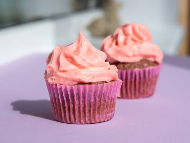 istock Cupcake with a lush pink cream cap on a purple table, with a place for text 1414277172