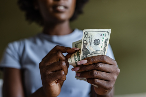 African American woman holding and counting dollars. Home budget planning.