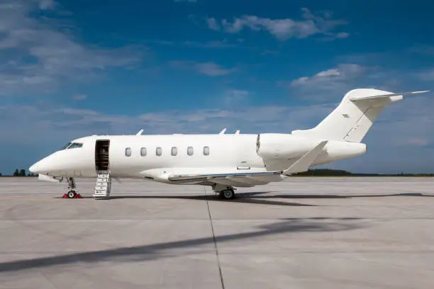 Modern white business jet with an opened gangway door at the airport apron