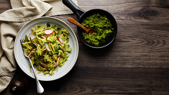 Homemade orzo and grilled asparagus salad serve with radish and vegan green pesto, rocket leaves.