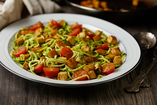 Homemade vegan courgetti with fried tofu, cherry tomatoes, and herb dressing.