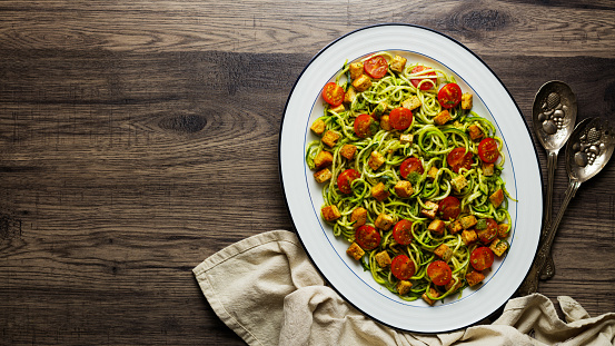 Homemade vegan courgetti with fried tofu, cherry tomatoes, and herb dressing.