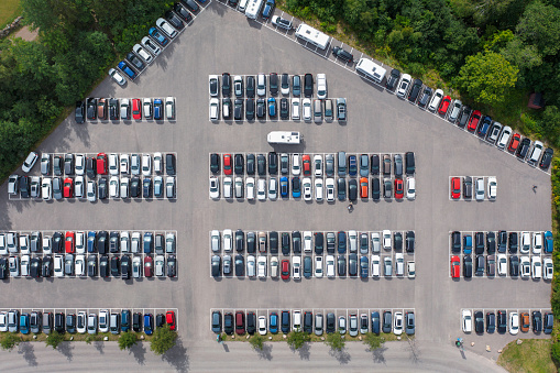 A full parking lot in summer, with an RV looking for space.