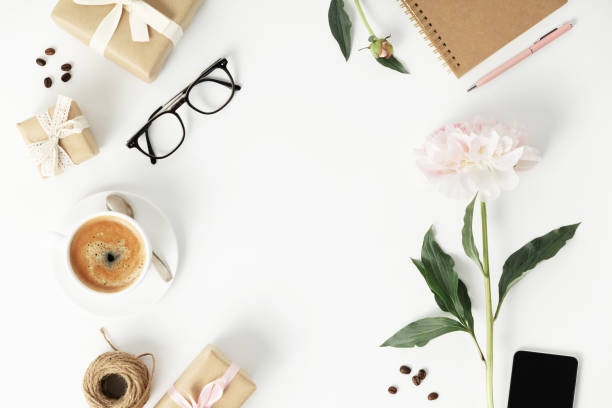 istock Festive arrangement: gift boxes, coffee, notebook, mobile phone, glasses and flowers  on a white table 1414281532