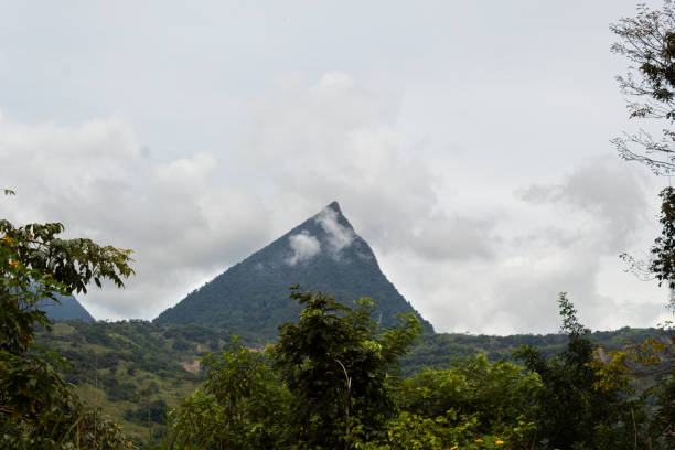 pyramidenförmiger berg mit wolken vorne und hinten mit viel vegetation im vordergrund. cerro tusa, antioquia, kolumbien - pyramid shaped stock-fotos und bilder