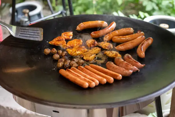 Photo of Meat balls, hot dogs and other meats on a large hot plate..