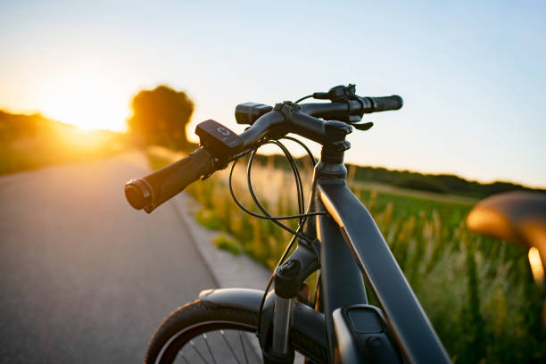 e-bike sulla strada di campagna al tramonto - wheel cycling nobody outdoors foto e immagini stock