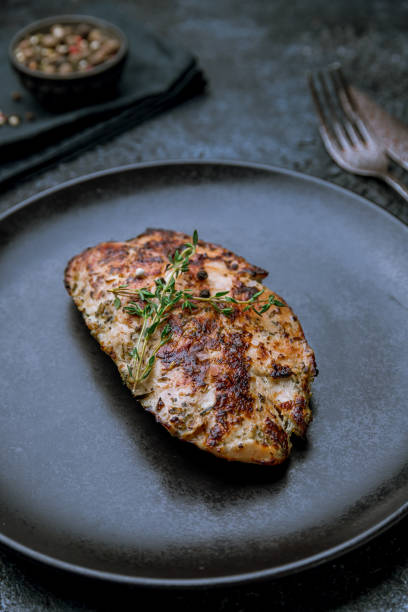 istock Grilled chicken Breasts on black plate on dark stone table macro close up vertical 1414282914