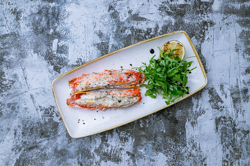King crab claws grilled with parmesan on plate on grey table top view