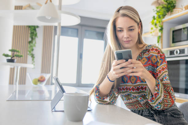 istock Woman using smart phone in dining room 1414284010