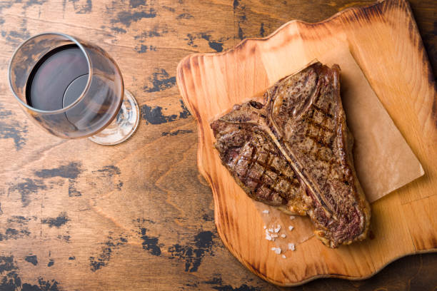 istock Steak T Bone, tibon steak, steak on bone on wooden table with red wine top view, copy space for text 1414284100