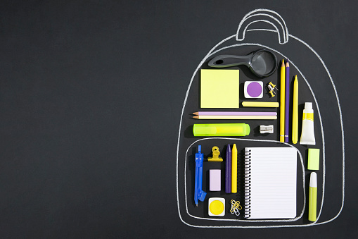 Back to school concept with chalk drawing backpack  with school supplies on chalkboard