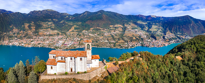 Scenic romantic lakes of Italy - Lago Iseo surrounded by beautiful mountains. Aerial view of small church in top of Monte isola island. Popular tourist attraction