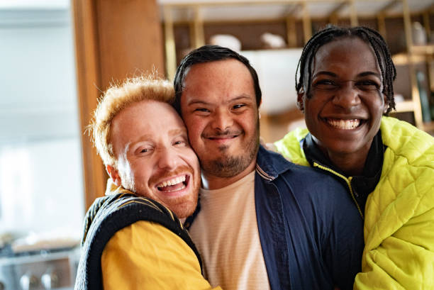 Portrait of a disabled young man and his friends embraced at home Portrait of a disabled young man and his friends embraced at home developmental disability diversity stock pictures, royalty-free photos & images