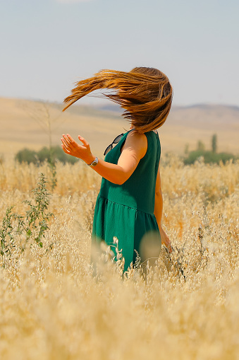 A woman tossing her hair in a field of oats