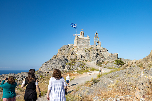 Tourists walking near the Church of Agios Paisios near Damnoni Beach in Rethymno Region on Crete, Greece
