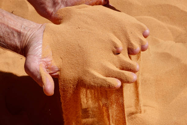 istock Pink coral sand running through his fingers 1414294642