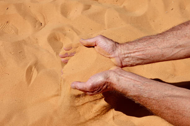 istock Man scooping up coral pink sand from the dune 1414294647